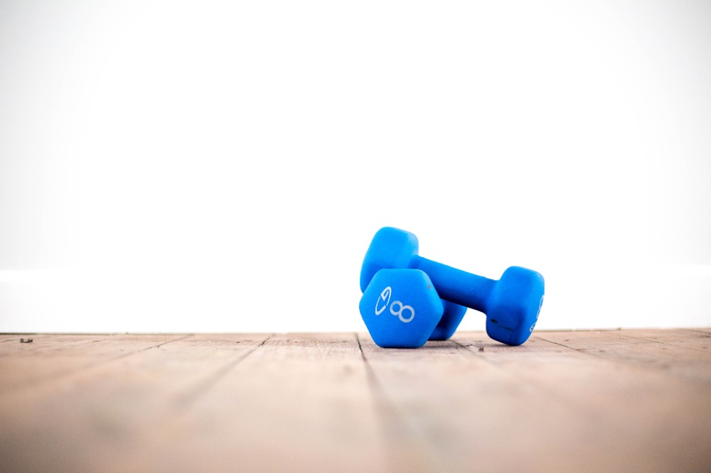 A pair of blue hand weights on a wooden floor