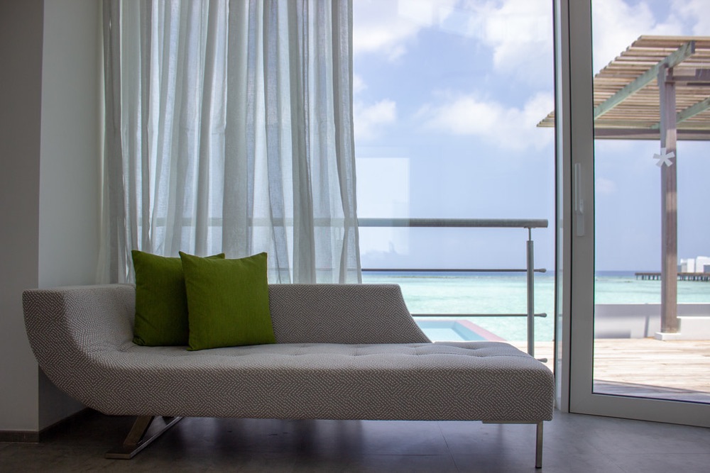 A daybed with two green cushions beside a bright window